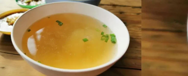 A bowl of homemade bone broth and vegetable soup with fresh herbs